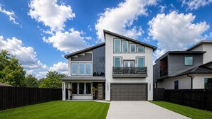 Een modern huis met twee verdiepingen, een ruime garage, een verzorgd gazon en een helderblauwe lucht.