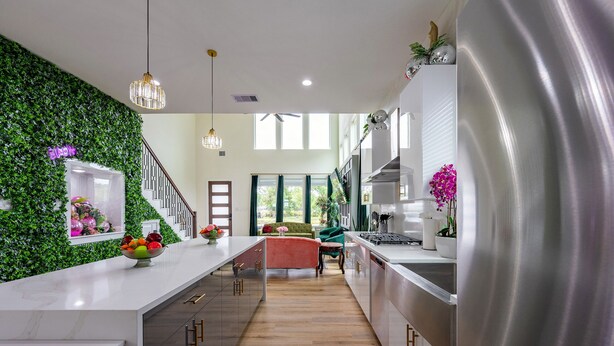 Een moderne keuken met een centraal eiland, een groene wand en een trap naar een woonruimte.