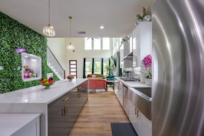 Une cuisine moderne dotée d’un îlot central, d’un mur végétal et d’un escalier menant à un espace de vie.