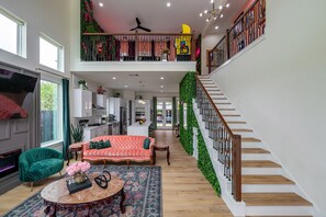 A spacious living area with a sofa, a coffee table, and a staircase leading to an upper level.