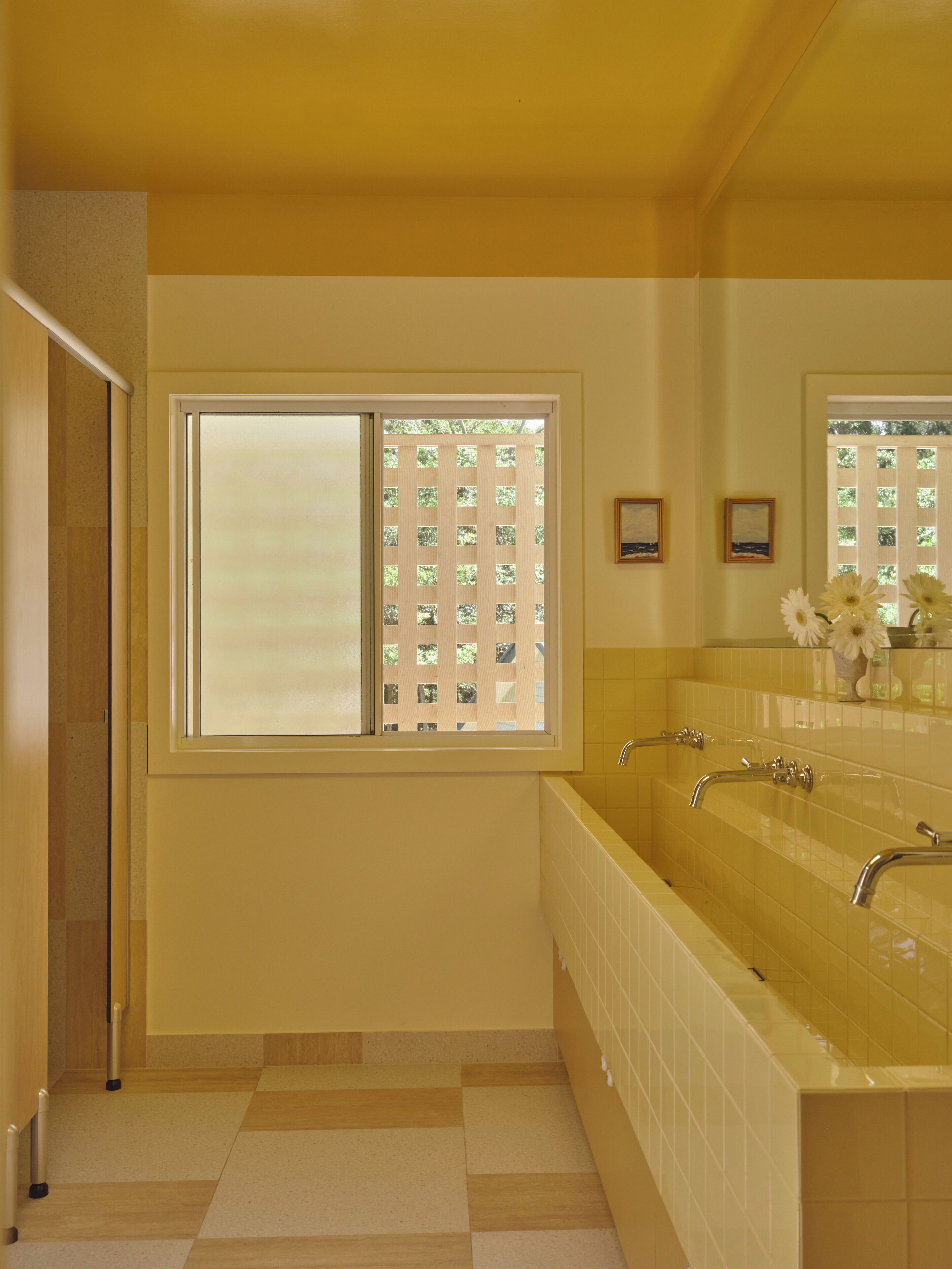 A bathroom with a large window, a double sink, and a mirror.