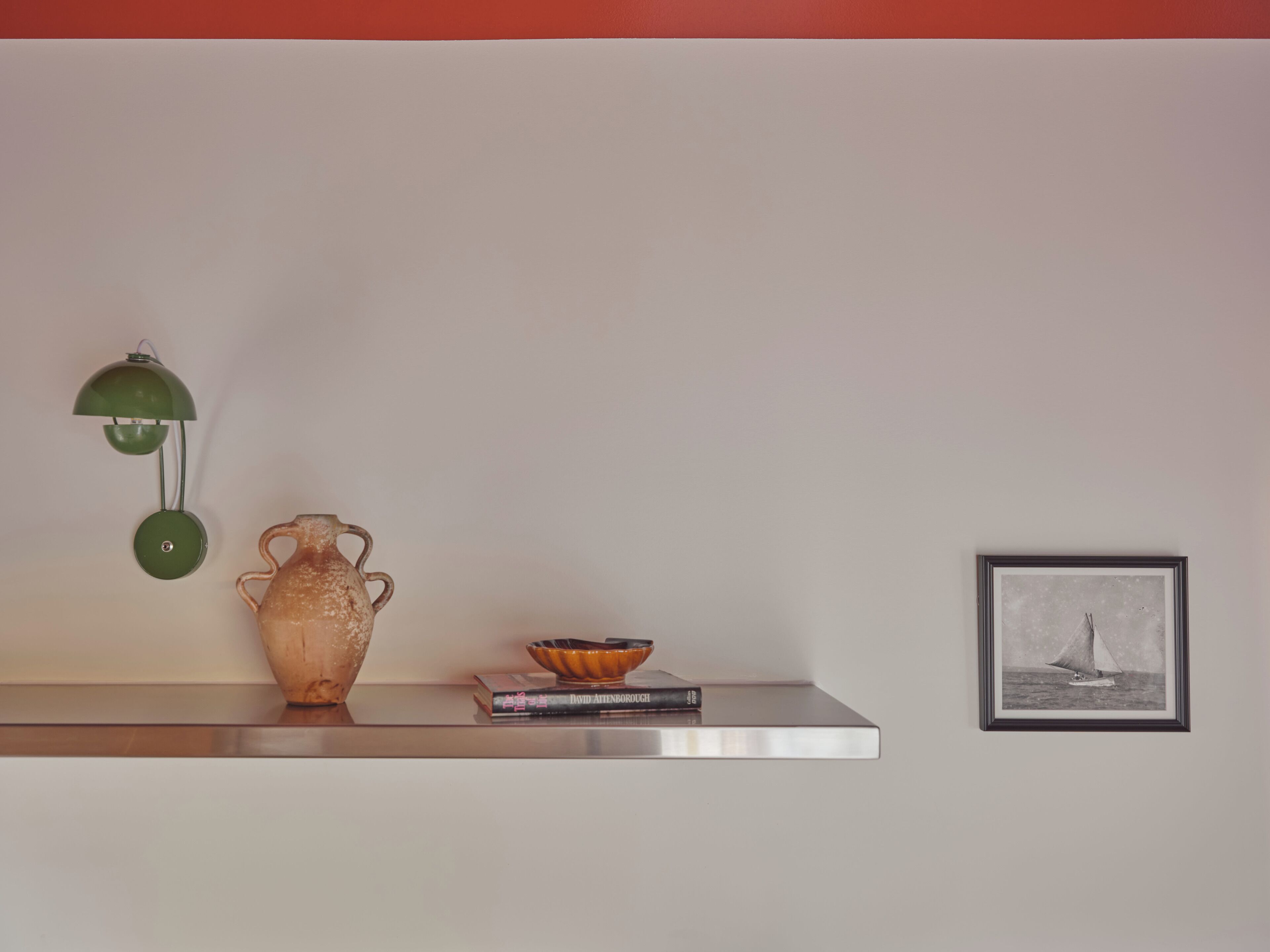 A shelf with a ceramic vase, a bowl, and a framed picture.