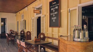 Un espace bar avec des meubles en bois et un tableau noir affichant les offres spéciales de l’happy hour.