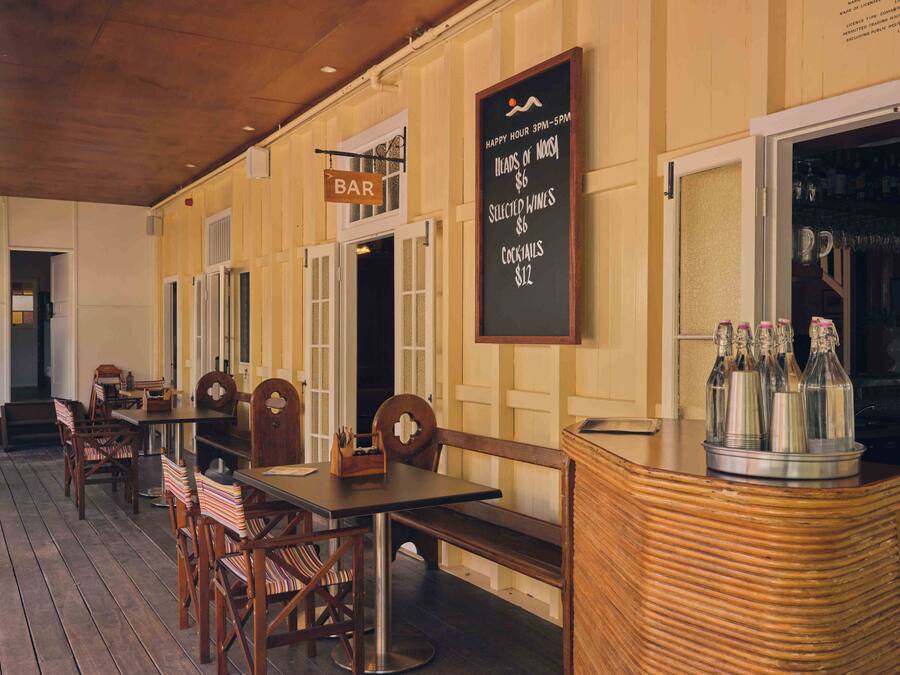 Un espace bar avec des meubles en bois et un tableau noir affichant les offres spéciales de l’happy hour.