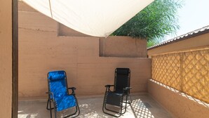 A covered outdoor area with two chairs, a wall, and a tree in the background. - Apartment 'Relax Porto Mannu' with Sea View, Wi-Fi and Air Conditioning (Palau)