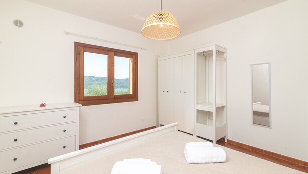 A bedroom with a bed, a wardrobe, a mirror, and a window with a view. - Apartment 'Relax Porto Mannu' with Sea View, Wi-Fi and Air Conditioning (Palau)