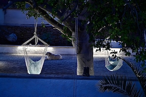 Two hammocks under a tree, a stone wall, and a dog lying on the ground. - Villa 'La Casa del Vento Plemmirio' with sea view, Wi-Fi and air conditioning (Plemmirio)