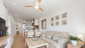 Un salon moderne avec un canapé, une table à manger et une cuisine en arrière-plan.