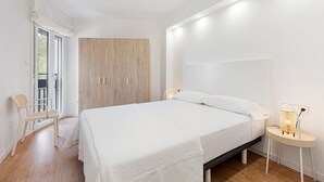 Une chambre à coucher moderne, dotée d’un grand lit, d’une armoire, d’une chaise et d’une table de chevet avec une lampe.