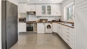A compact kitchen with white cabinets, a stainless steel refrigerator, a microwave, a dishwasher, and a washing machine.
