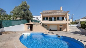 A two-story house with a swimming pool and a covered garage.