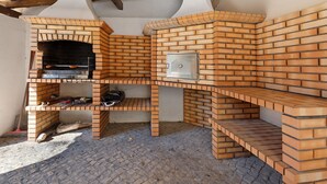 A brick-built outdoor kitchen with a pizza oven, a grill, and a built-in cooler.