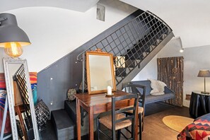 A staircase with a black metal railing, a wooden dining table with chairs, a sofa, and a lamp. - Villa 'Cangiani - La Heia' with Mountain View, Shared Terrace and Wi-Fi (Massa Lubrense)