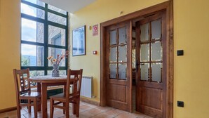 Uma área de refeições com uma mesa, cadeiras, uma janela com vista e uma porta de madeira.