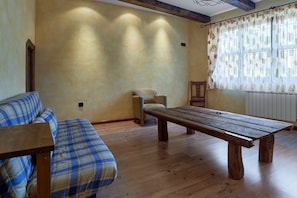 Una habitación con un banco de madera, un sofá escocés y una silla.