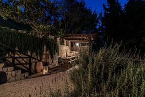 Ein Steinhaus mit einer Holzpergola, einem Kiesweg und einer Laterne.