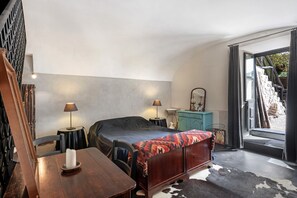 Un dormitorio con cama, mesitas de noche, cómoda y ventana con vistas al exterior.