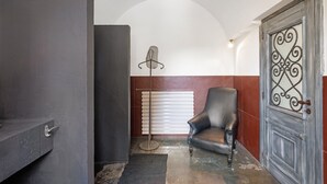 A room with a dark-colored door, a radiator, a chair, and a floor lamp. - Studio Apartment 'Villa Cangiani - La Lavanda' with Mountain View and Wi-Fi (Massa Lubrense)