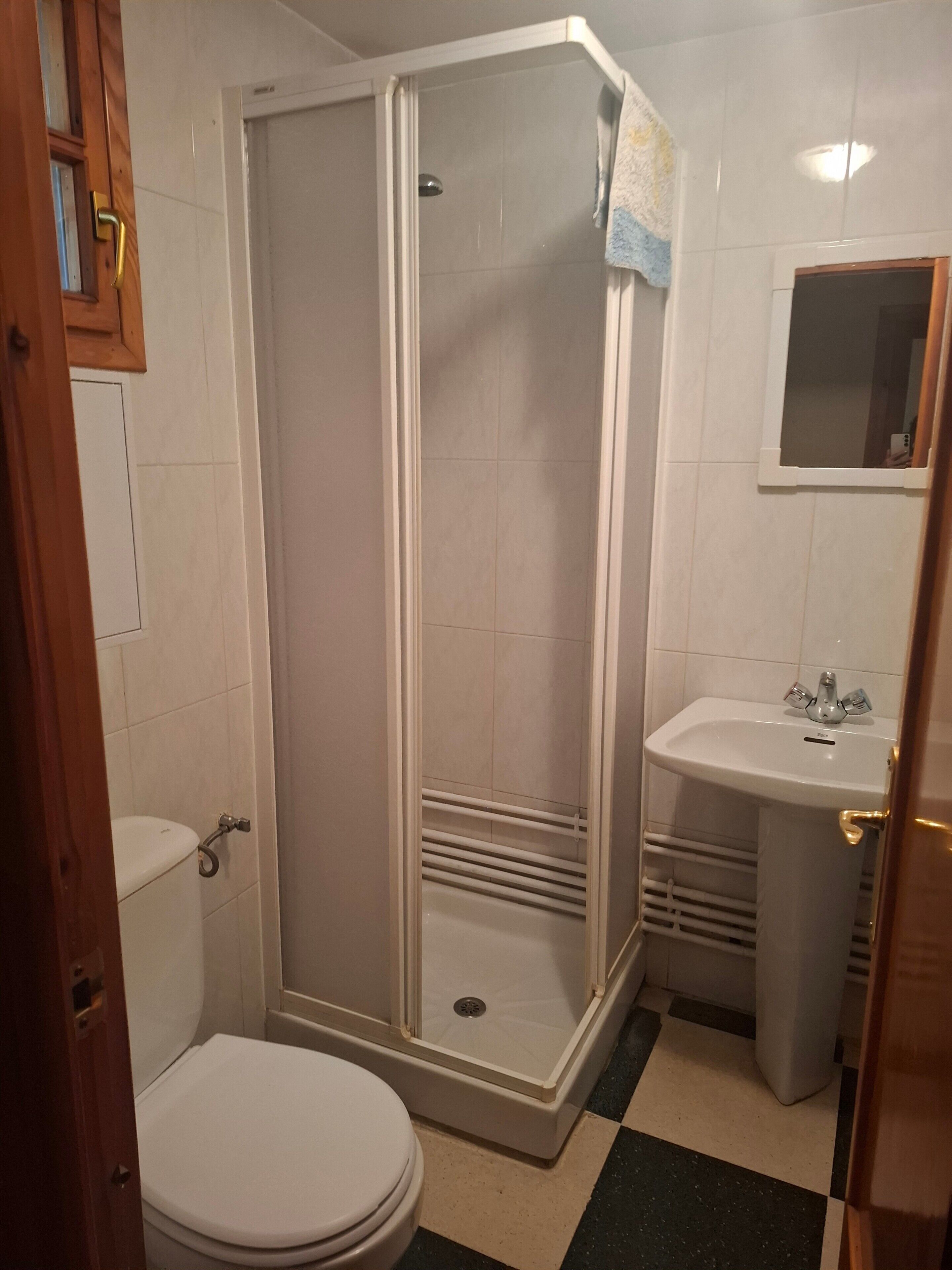 Ein Badezimmer mit Duschkabine, Toilette, Waschbecken und Spiegel.