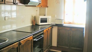 A kitchen with wooden cabinets, a microwave, a toaster, and a clock on the wall. - Holiday Home 'La Casa De Luis' with Mountain Views, Private Terrace and Wi-Fi (Castiello De Jaca)