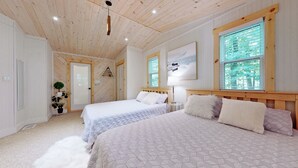Camera da letto con due letti, soffitto in legno e finestra con persiane.