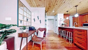 Una cucina moderna con mobili in legno, un angolo bar e una zona salotto con una poltrona in pelle.