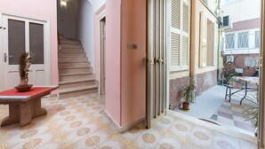 A hallway with a staircase, a bench, and a door leading to an outdoor area with a table and chairs. - Studio 'Pistiddu' with Shared Garden, Wi-Fi, and Air Conditioning (Dorgali)