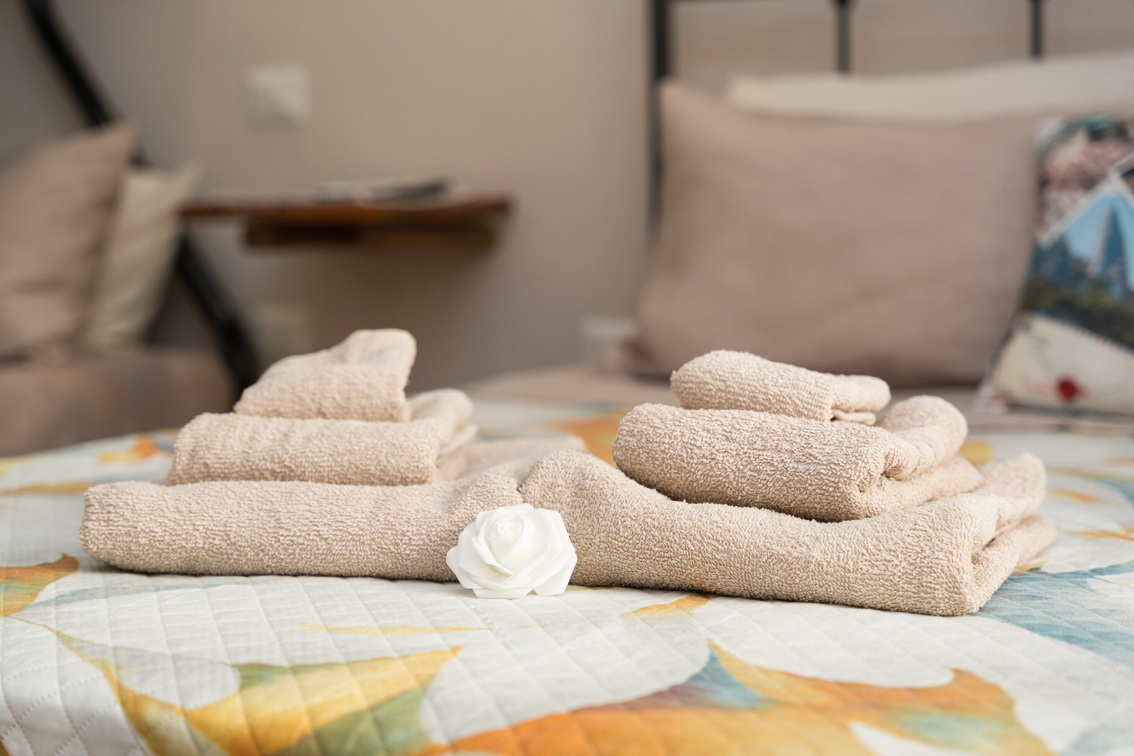 Um conjunto de toalhas dobradas com cuidado sobre uma cama com colcha estampada de flores.