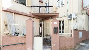 A building with a gated entrance, a balcony with a railing, and a table with chairs outside. - Studio 'Pistiddu' with Shared Garden, Wi-Fi, and Air Conditioning (Dorgali)