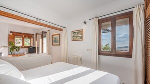 Un dormitorio con una cama grande, televisión, radiador y ventana con vistas.