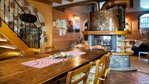 A wooden dining table with chairs, a stone wall, and a staircase. - Chalet 'Baita  Alabama' with Mountain View, Private Terrace and Wi-Fi (Arsiè)