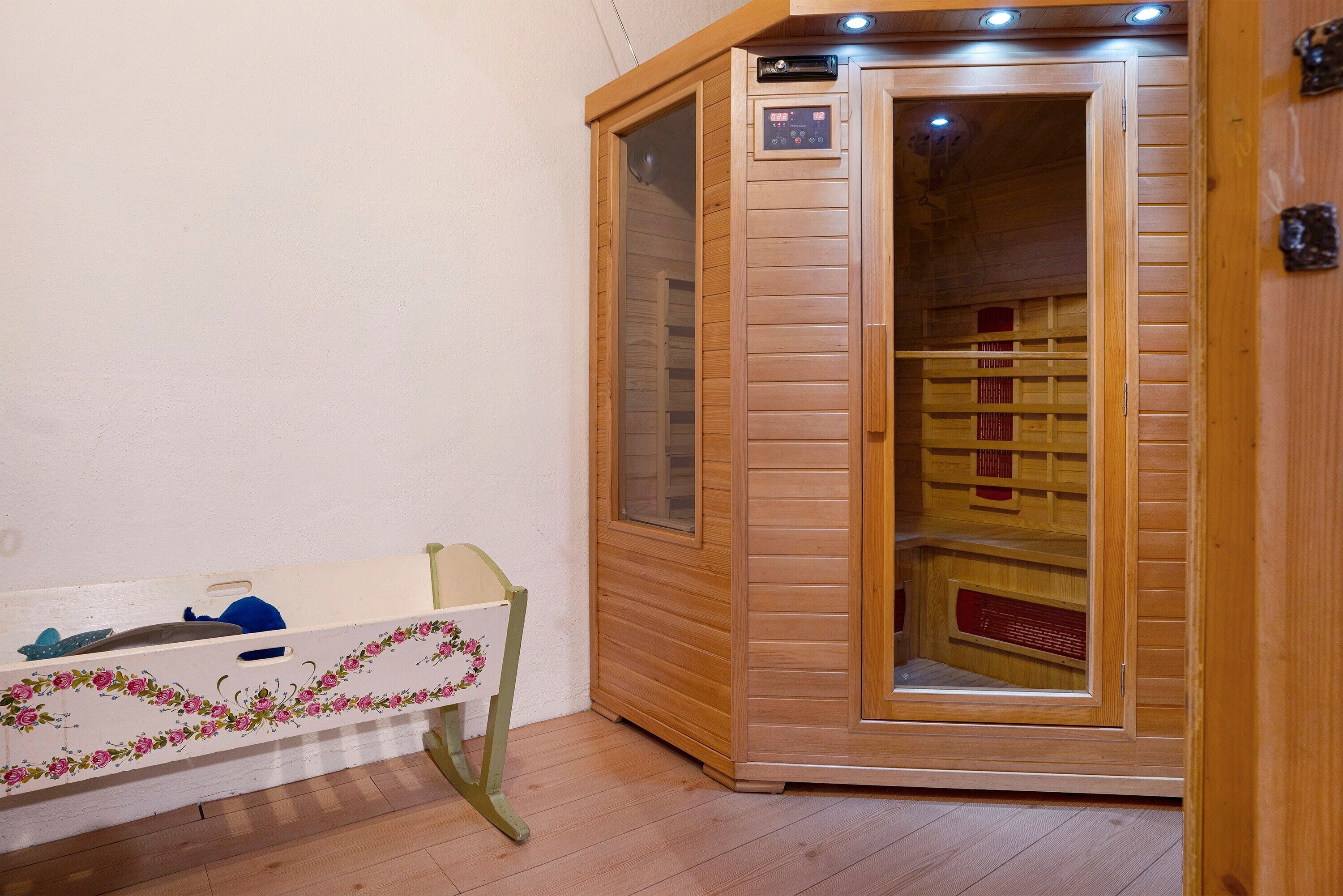 Una sala de sauna con puerta de madera, panel de control y banco con diseño floral.