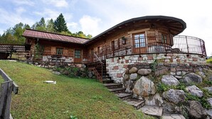 A wooden cabin with a stone foundation, a curved roof, and a stone staircase leading to a wooden deck. - Chalet 'Baita  Alabama' with Mountain View, Private Terrace and Wi-Fi (Arsiè)