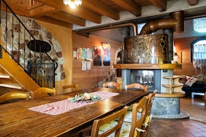 A wooden dining table with chairs, a stone wall, and a staircase. - Apartment 'Original' with Mountain View, Private Garden and Wi-Fi (Arsiè)