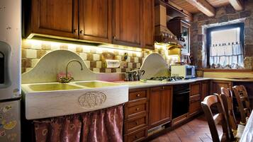 A kitchen with wooden cabinets, a marble countertop, and a window with curtains.