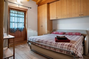 Un dormitorio con cama, armario de madera y ventana con cortinas.