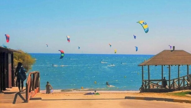 Una playa con una estructura de madera, una zona arenosa y el mar.