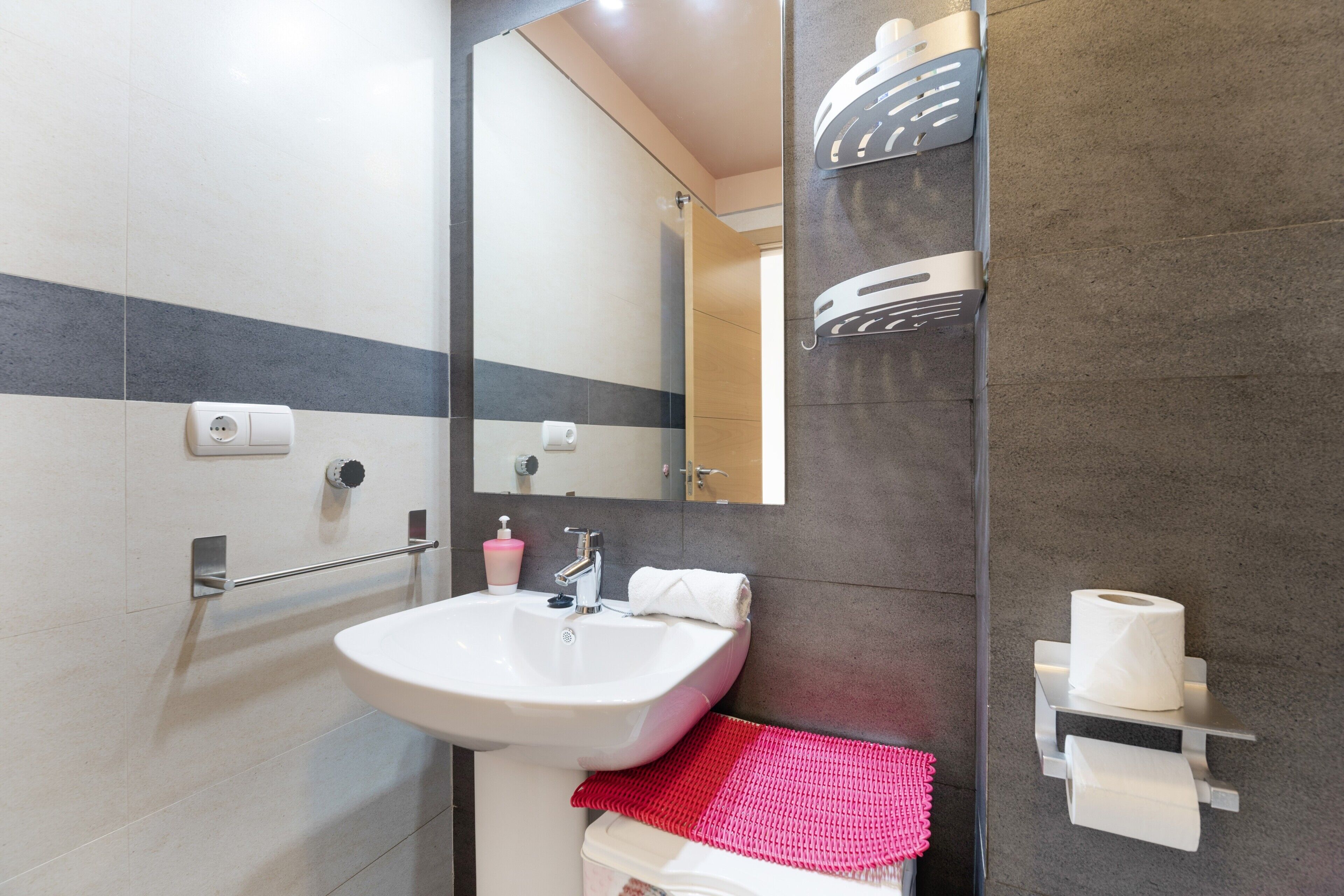 Une salle de bain équipée d’un lavabo, d’un miroir, d’un porte-serviettes et d’un support à papier toilette.