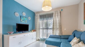 Una sala de estar moderna con sofá, televisor y decoración mural.
