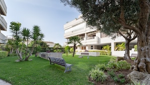 Un patio con un banco, palmeras y un edificio con balcones.