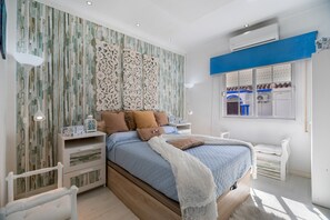A bedroom with a bed, nightstands, a window, and a decorative wall panel. - Apartment 'Casa Margara' with Wi-Fi and Air Conditioning (Chipiona)