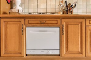 A kitchen with wooden cabinets, a Bosch dishwasher, and a tiled backsplash. - Cottage 'Gite Saint Guiral' with Mountain View, Private Terrace and Private Garden (Dourbies)