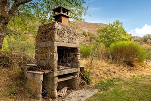 A stone structure with a chimney, surrounded by natural vegetation and hills. - Cottage 'Gite Saint Guiral' with Mountain View, Private Terrace and Private Garden (Dourbies)