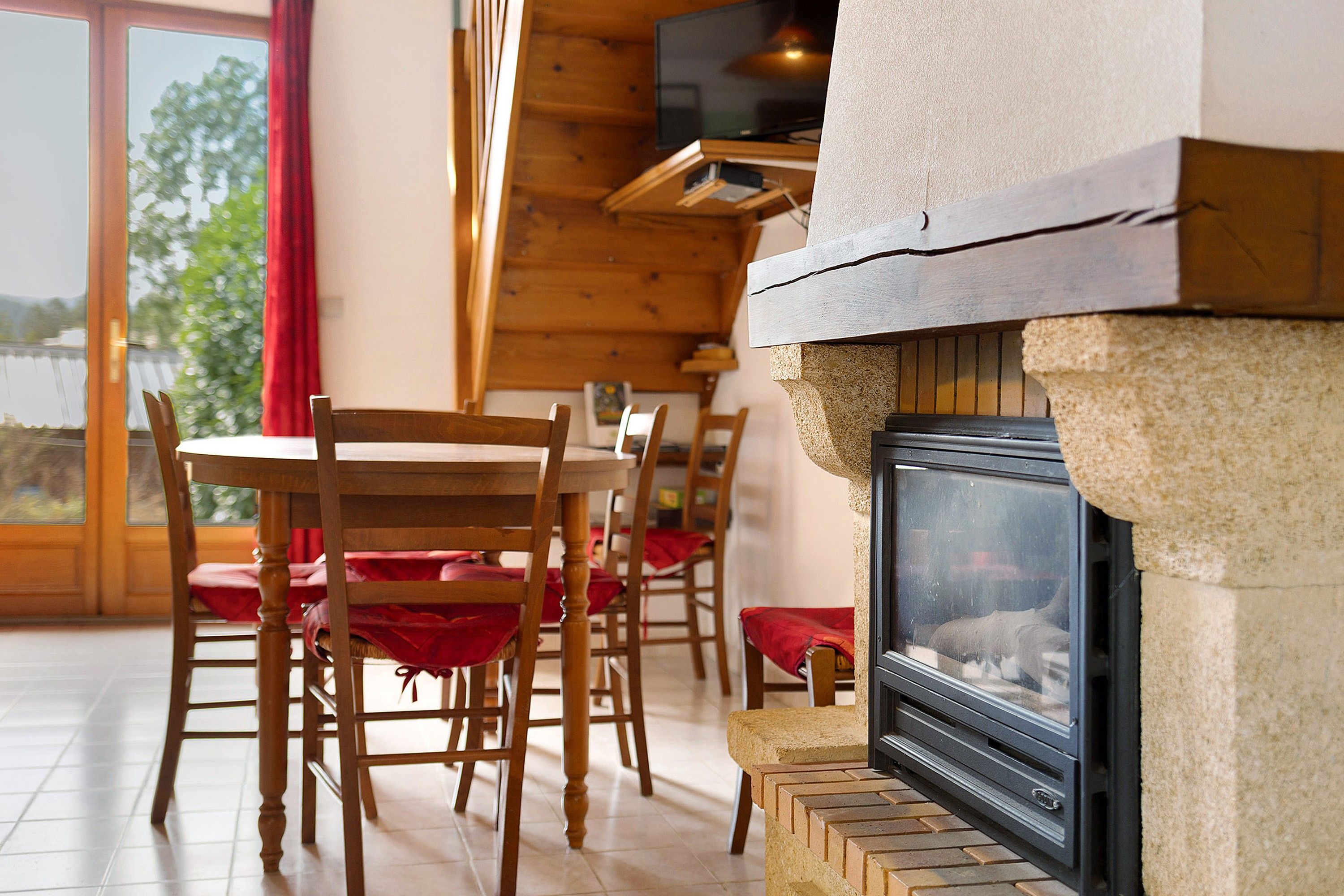 A room with a fireplace, wooden chairs, and a dining table.