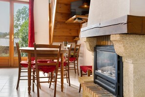 A room with a fireplace, wooden chairs, and a dining table. - Cottage 'Gite Saint Guiral' with Mountain View, Private Terrace and Private Garden (Dourbies)
