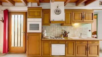 Een keuken met houten kastjes, een Bosch vaatwasser, een fornuis en een klok aan de muur.