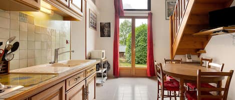 Une cuisine avec des meubles de rangement en bois, un évier et un coin repas comprenant des chaises et une table.