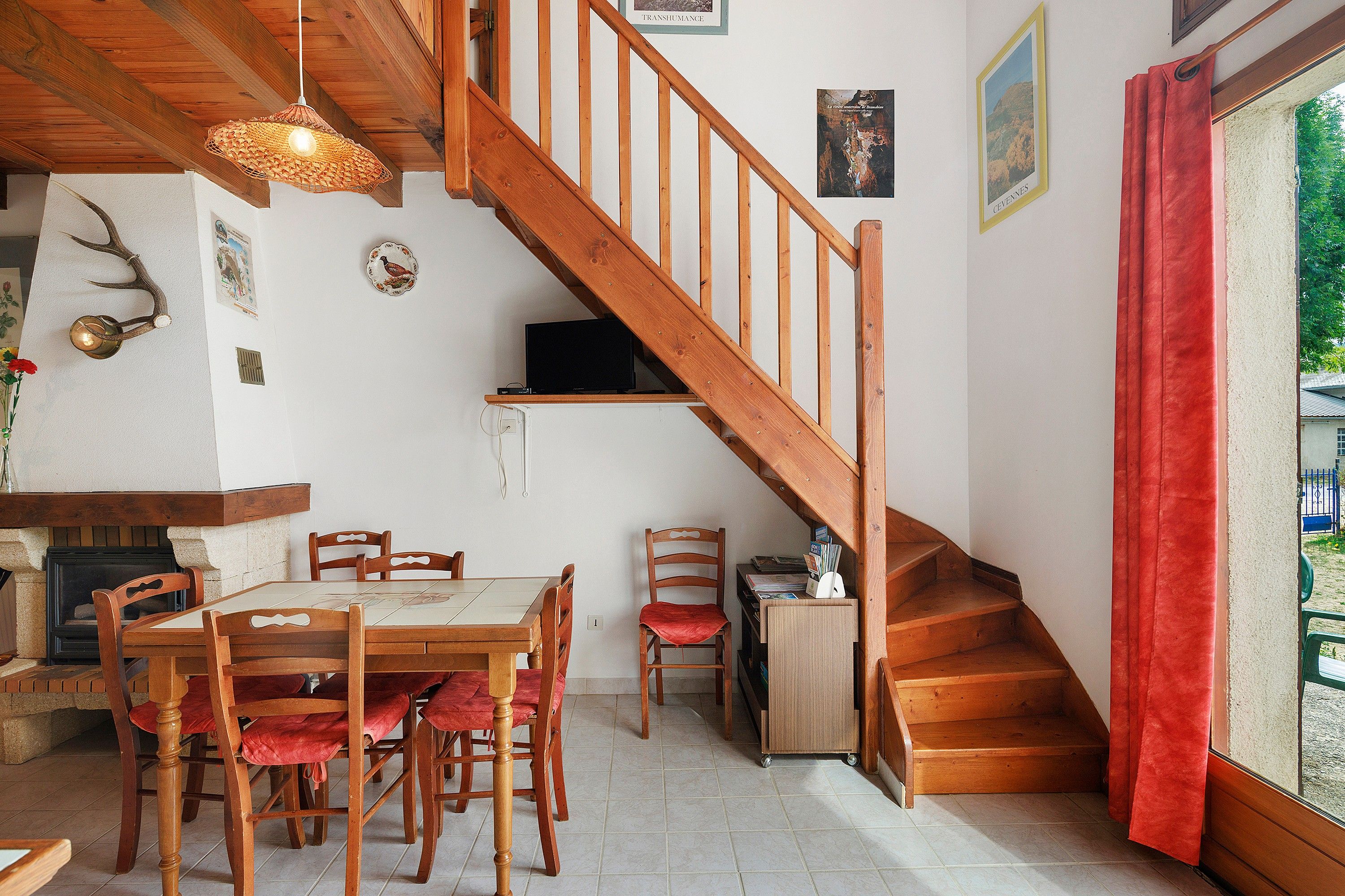 A dining area with a wooden table and chairs, a fireplace, and a staircase leading to an upper level.