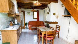 A kitchen with wooden cabinets, a dining table with chairs, a sofa, and a staircase. - Holiday Home 'Gîte Le Suquet' with Mountain View and Private Terrace (Dourbies)