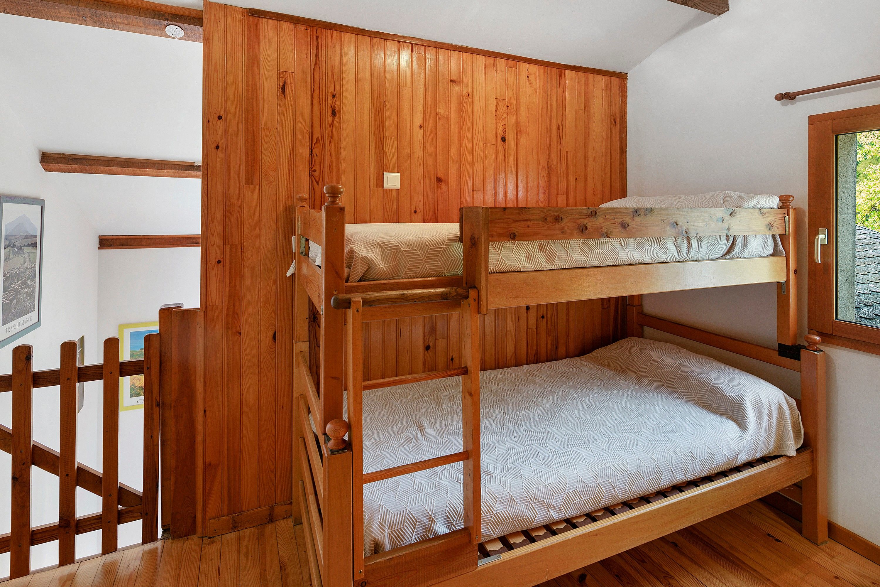 Un lit superposé avec une structure en bois et un matelas à motifs.